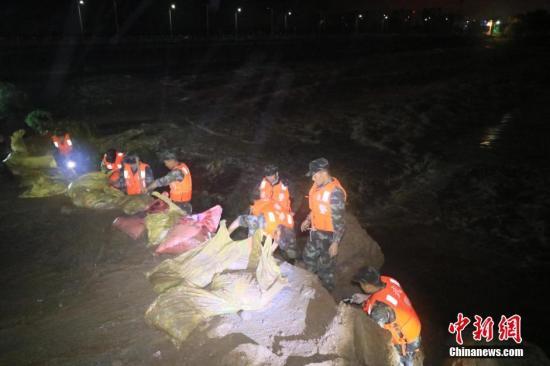 抢险人员在麻城城区举水二桥橡胶坝处装填沙袋，填补塌陷空缺。 何智利 摄