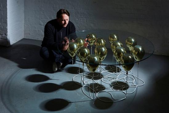 好生活介绍过 Duffy London 的创始人克里斯托弗·达菲（Christopher Duffy）在2012年设计的悬漂咖啡桌，彼时的长方形咖啡桌在时隔三年后的如今摇身变成圆形、并新增加红色气球的款式，组成2015版系列重现江湖 。杂乱有章的钢筋绳、金属与树脂复合气球 、以及钢化玻璃台面共同造就了奇妙的错视感 。气球颜色有金、银、红三色，也可混合搭配，但起价8300美元，限量25张。