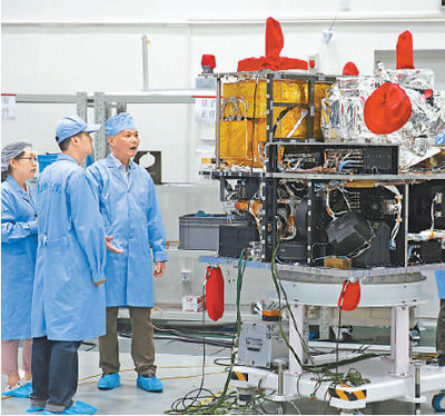 量子科学实验卫星副总设计师周依林（左三）与工作人员在量子卫星旁忙碌。