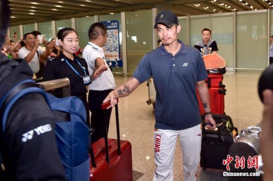 8月22日，中国奥运羽毛球队抵达首都机场，被早已等候在现场的球迷层层包围。图为林丹走出机场，受到好友鲍春来的热情迎接。 中新网 图
